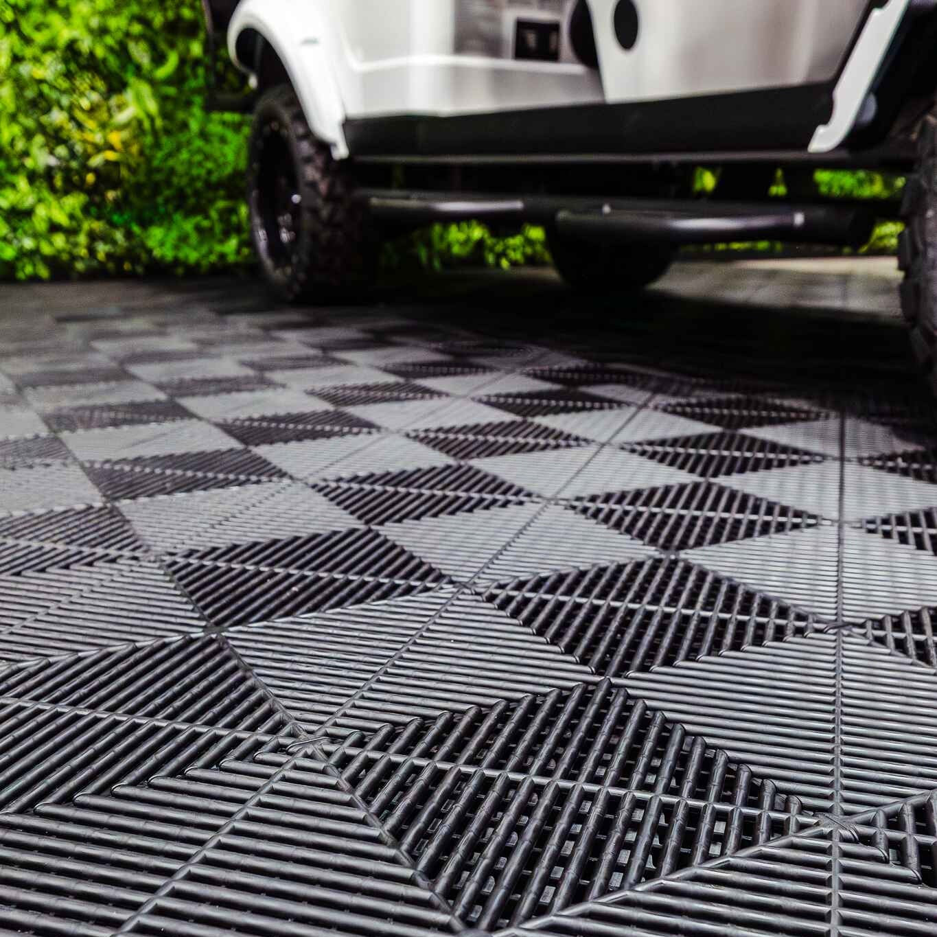 Close-up of a textured black and white checkered floor with a vehicle partially visible.