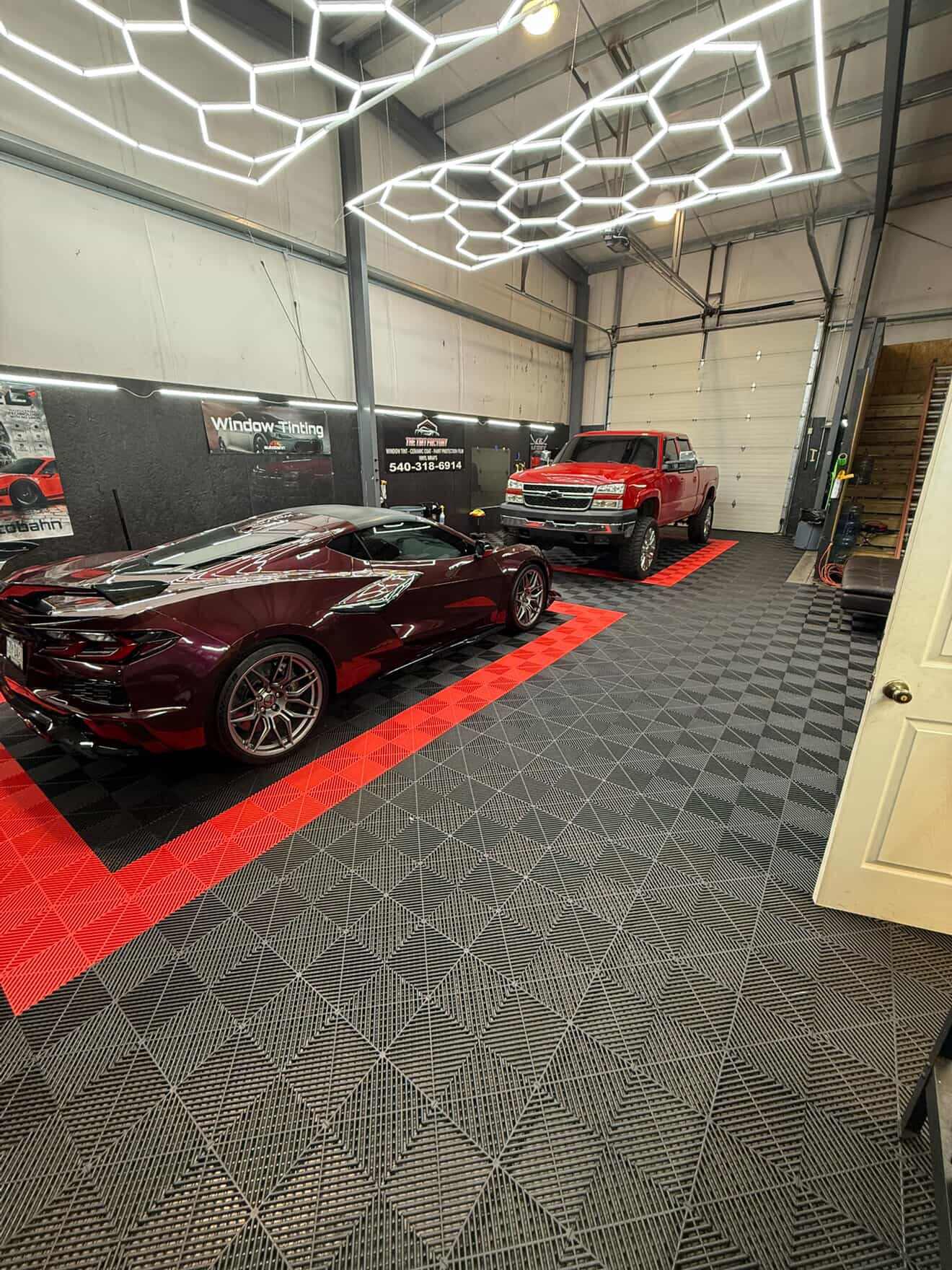 Garage interior with a red sports car and a red pickup truck.