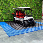 White golf cart with red seats on a blue checkered mat in front of a green wall.